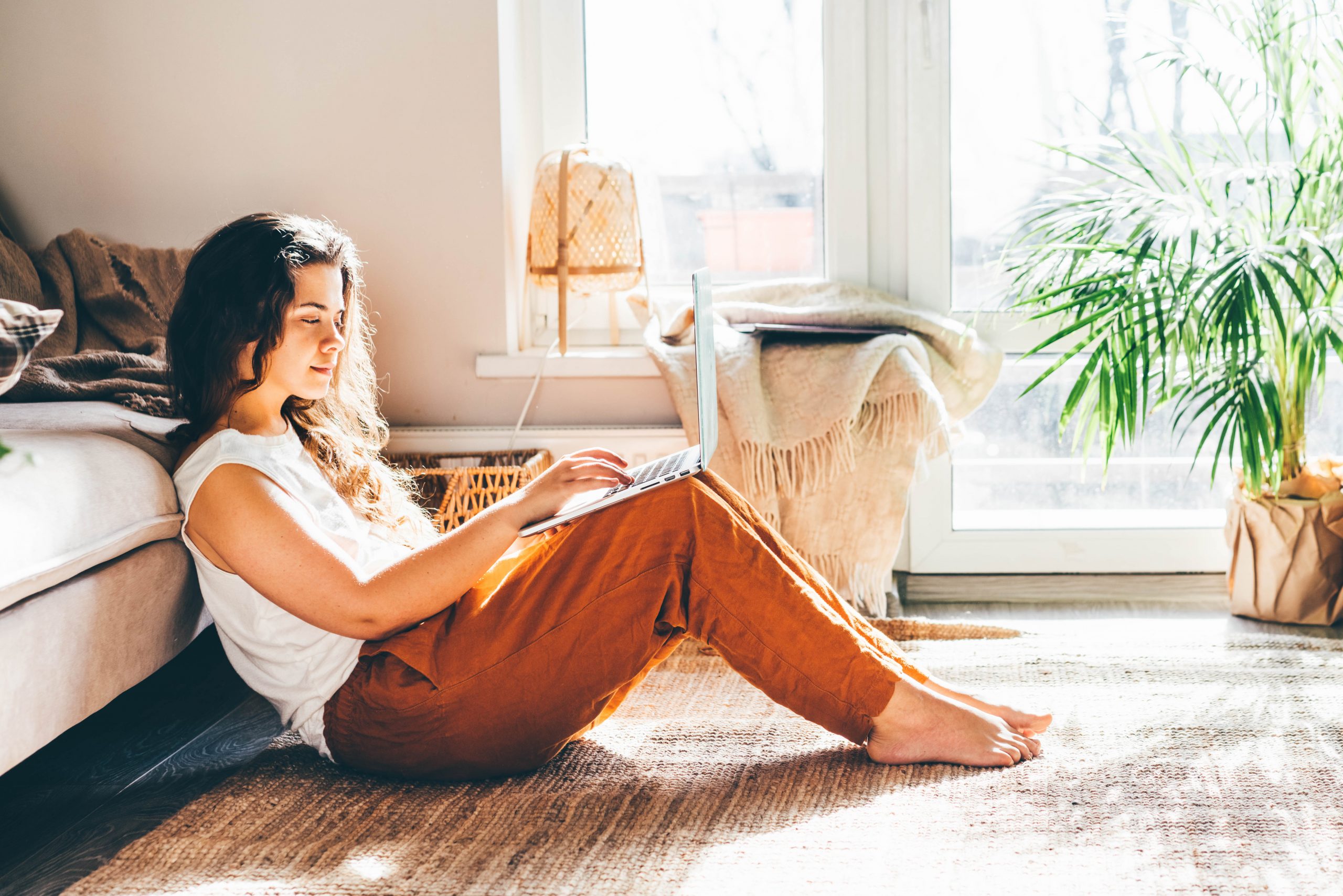 Young woman working from home. Girl using laptop at sunny room.